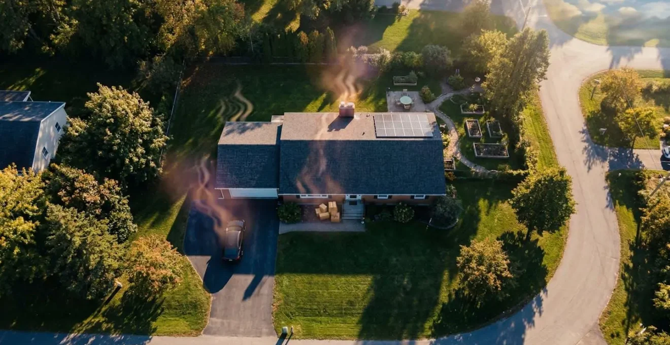 Vue aérienne d'une maison avec visualisation symbolique des sources d'émissions carbone du quotidien